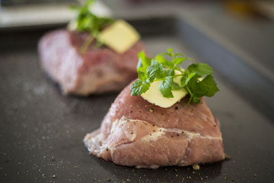 Close-up of meat with butter and mint leaves in baking tray