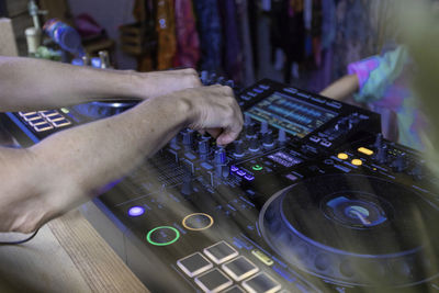 Cropped hands of man opening sound mixer in nightclub