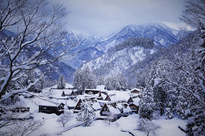 High angle view of snow covered houses and trees by mountains