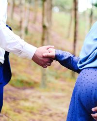 Midsection of pregnant woman holding husband hand