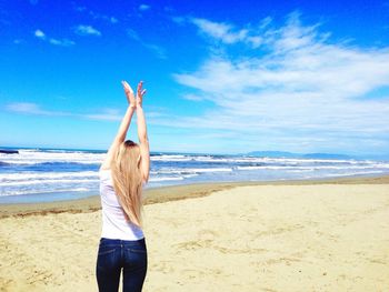 Woman standing at beach against blue sky