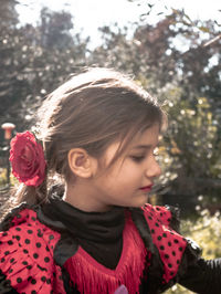 Cute girl wearing rose looking away at park