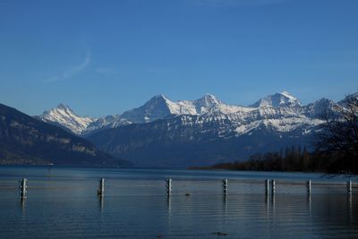 Scenic view of lake by snowcapped mountains against sky