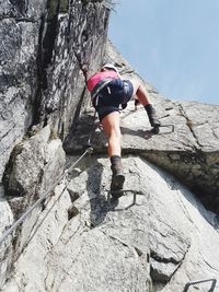 Full length rear view of woman climbing on rock