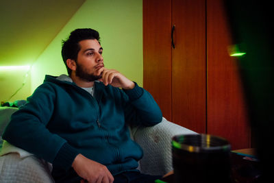 Young man looking away while sitting on table