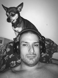 Portrait of man wearing headphones sitting with chihuahua on sofa at home
