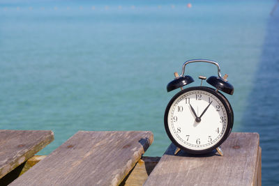 Close-up of clock on table by sea