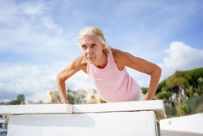 Low angle view of young woman looking away against sky