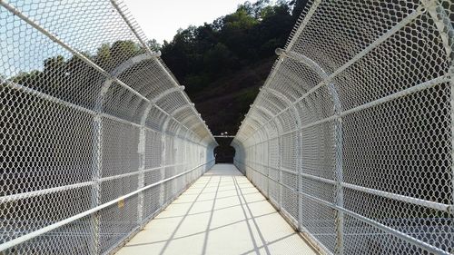 Walkway amidst railings during sunny day