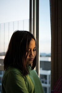 Portrait of smiling young woman looking through window