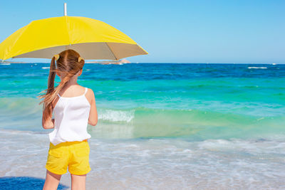 Rear view of young woman standing on beach