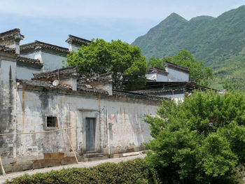 Plants growing on old building by tree mountain against sky