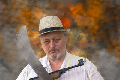 Close-up portrait of man with machete and gun standing outdoors