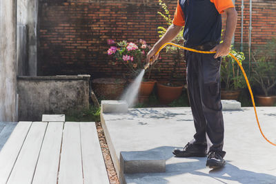 Termite controler spraying cemicals outside the house into the soil and wooden deck.