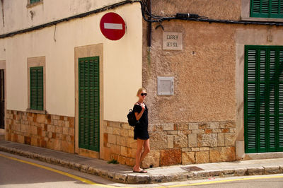 Full length of woman standing against building in city