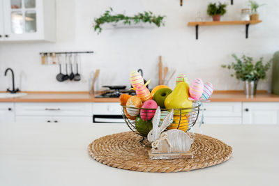 Easter bunny and basket with fruits and eggs on white table in scandinavian-style kitchen