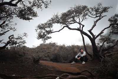 Man with dog by trees against sky