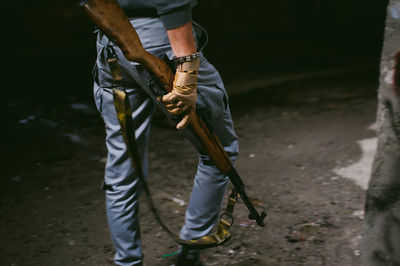 Midsection of man holding rifle