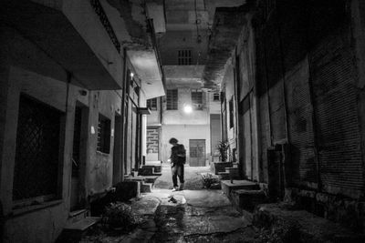 Man walking in illuminated alley at night