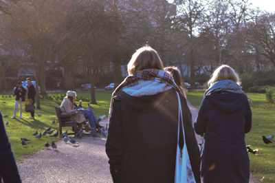 Rear view of people walking on bare trees