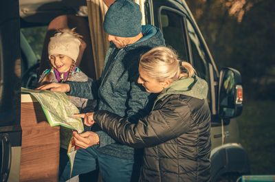 Parents with daughter analyzing map at motor home