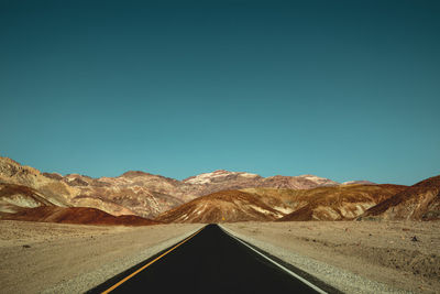 Road amidst desert against clear sky