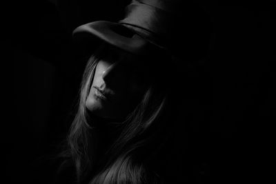 Close-up of young woman against black background