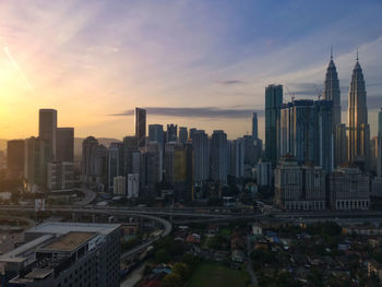 Modern buildings in city against sky during sunset