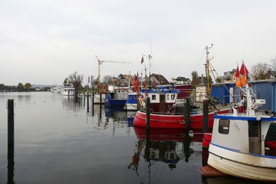 Boats moored at harbor against sky