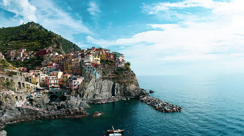 Aerial view of townscape by sea against sky