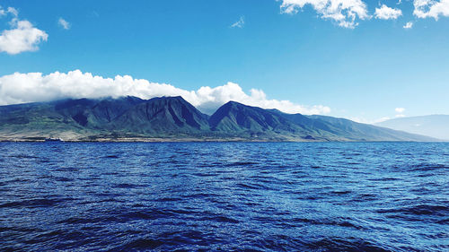 Scenic view of sea and mountains against blue sky