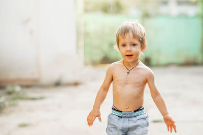 Portrait of shirtless boy standing outdoors