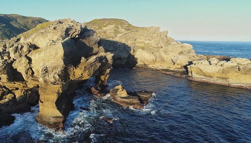 Rocks in sea against clear sky