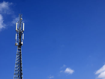 Low angle view of communications tower against blue sky