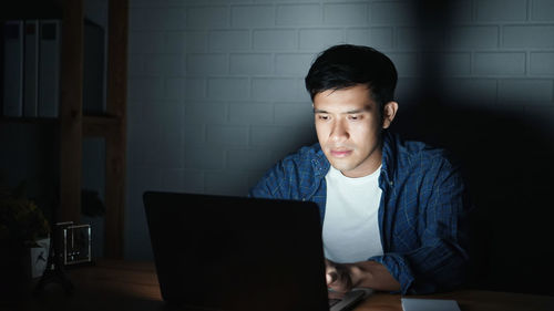 Young man using mobile phone while sitting on table