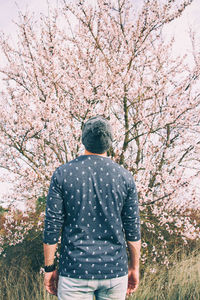 Rear view of man standing against cherry tree