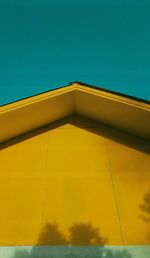 Low angle view of yellow building against clear blue sky