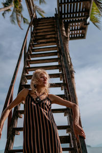 Low angle view of young woman standing on staircase