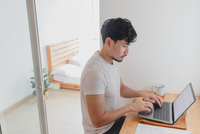 Young man using mobile phone while sitting on table