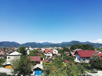 High angle view of houses in town against clear blue sky