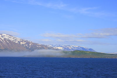 Scenic view of sea and snowcapped mountain against sky