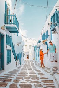 Woman talking to man while standing in balcony against sky