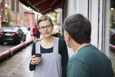 Confident female having coffee with male coworker outside art studio