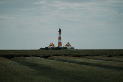 Lighthouse on field against sky