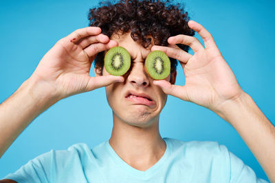 Portrait of young woman holding apple against blue background