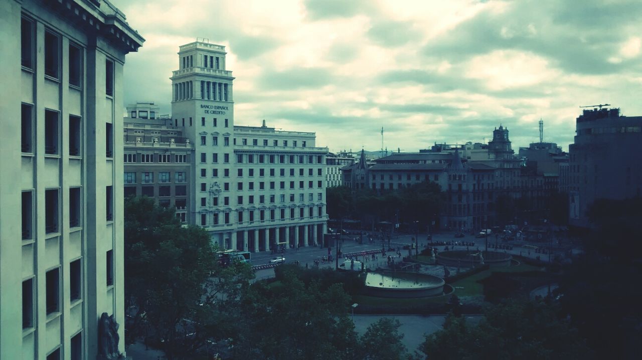 building exterior, architecture, built structure, sky, city, cloud - sky, building, cloudy, residential building, transportation, modern, cloud, tree, office building, day, city life, mode of transport, outdoors, residential structure, skyscraper