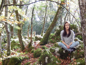 Portrait of young woman sitting on in forest