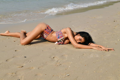 Young woman lying on sand at beach