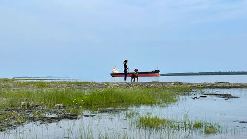 People sitting by sea against sky