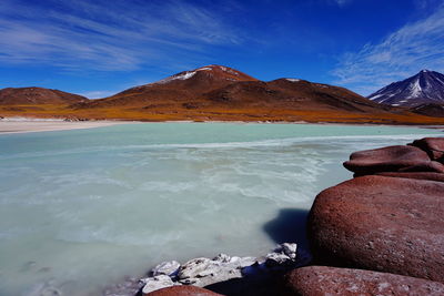 Scenic view of sea by mountains against sky